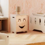 Armoire pour enfants en bois avec un visage souriant aux yeux fermés s’ouvrant vers la gauche en couleur cachemire