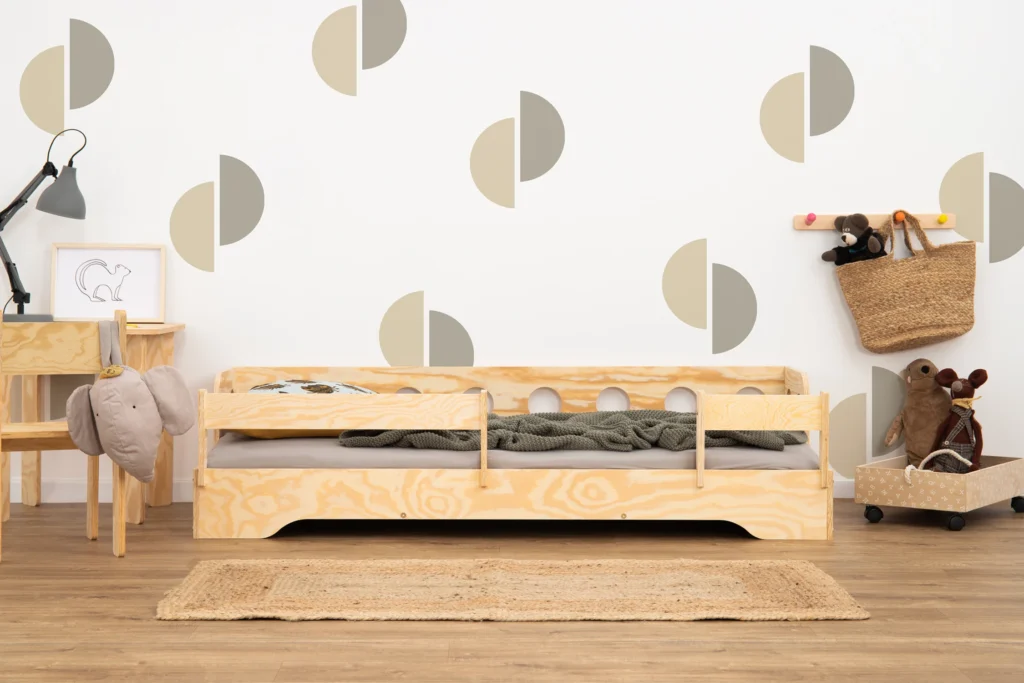 Lit en bois de couleur bois naturel avec des découpes dans les barrières latérales et équipé de barrières supplémentaires