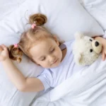 Enfant dormant paisiblement dans un lit, avec un doudou