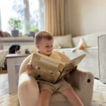 Enfant lisant un livre et assis sur un siège BUBU dans une chambre
