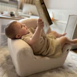 Enfant lisant un livre et assis sur un siège BUBU dans une chambre