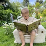 Enfant lisant un livre et assis sur un siège BUBU dans le jardin