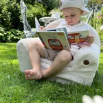 Enfant lisant un livre et assis sur un siège BUBU dans le jardin
