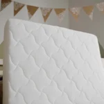 Matelas enfant blanc présenté à la verticale dans une chambre d’enfant.