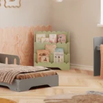 Bibliothèque Lulu de couleur verte placée à côté du lit gris dans une chambre d’enfant, avec les livres bien visibles et accessibles.