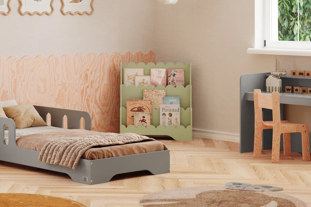 Bibliothèque Lulu de couleur verte placée à côté du lit gris dans une chambre d’enfant, avec les livres bien visibles et accessibles.