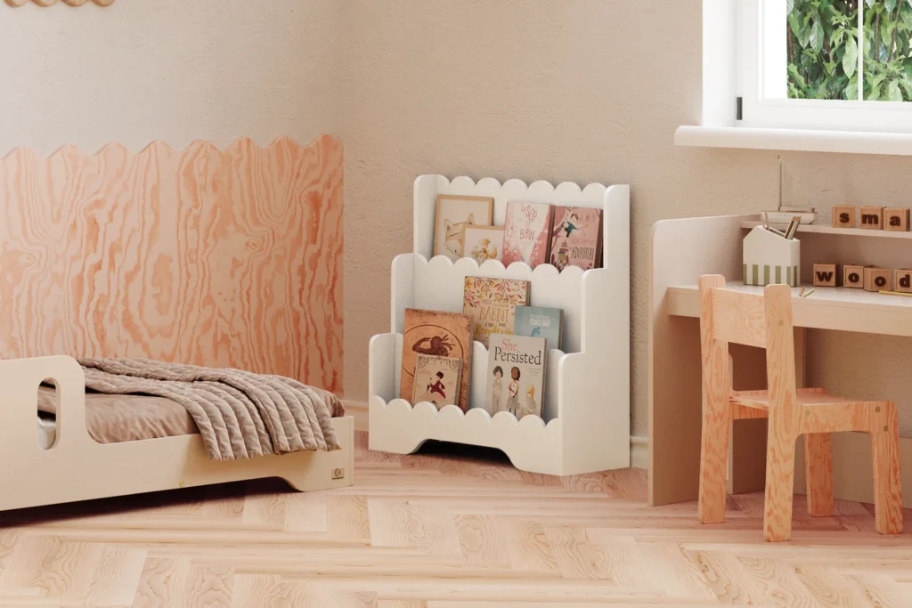 Bibliothèque Lulu blanche placée près de la fenêtre dans une chambre d'enfant, avec un lit et un bureau assortis cachemire. Espace lumineux et décor doux.