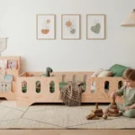 Lit bébé TILA 2 en bois naturel dans une chambre d’enfant lumineuse, style moderne et rustique, avec enfant jouant sur un tapis