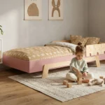 Chambre enfant avec un lit en bois PUZZLE BR1 rose - petite fille jouant avec des blocs en bois à côté de son lit Montessori