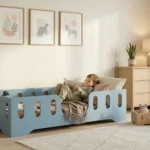 Chambre enfant avec un lit Montessori TILA 2 bleu avec barrière - garçon lisant un livre confortablement installé dans son lit sécurisé