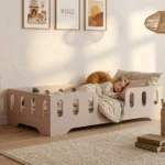 Lit enfant Smartwood TILA 2 en bois rose poudré avec barrières dans une chambre style hygge - petite fille endormie, ambiance chaleureuse et cocooning.