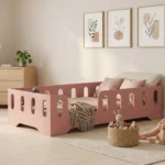 Lit enfant Smartwood TILA 2 en bois rose avec barrières dans une chambre vintage lumineuse - enfant jouant avec des cubes en bois à côté du lit.