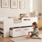 Lit enfant Smartwood PIPI blanc avec tiroir et barrière - petite fille jouant avec des cubes en bois à côté du lit.