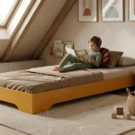 Lit enfant TILA 7 bas en bois jaune moutarde sous les combles, garçon lisant un livre dans une chambre cosy aux pentes douces.
