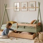 Lit tipi TIPI D vert en bois avec tiroir coulissant, fillette sortant des cubes du tiroir dans une chambre d'enfant lumineuse.