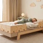 Lit enfant PUZZLE BR2 cachemire avec barrières en forme de puzzle, un garçon dort blotti contre un coussin.