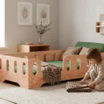 Lit enfant TILA 2 en bois naturel avec barrières, garçon pliant une couverture près du lit dans une chambre lumineuse.