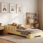 Lit enfant TILA 6 jaune beurre avec barrière, petite fille endormie sous une couverture dans une chambre lumineuse.