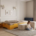 Lit enfant TILA 8 jaune moutarde avec barrières, coussins et couvre-lit devant un mur rayé dans une chambre colorée.