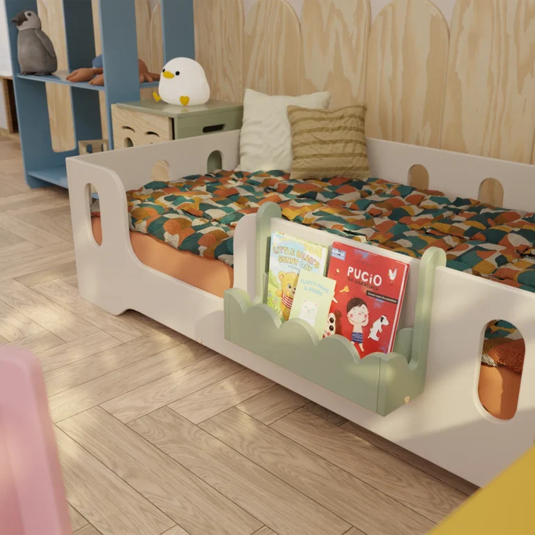 Étagère à livres verte LULI, suspendue à la barrière d’un lit pour enfant.