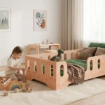 Lit enfant TILA 2 en bois naturel avec barrière tout autour et entrée à gauche, petite fille jouant aux cubes sur le tapis.