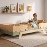 Lit enfant PUZZLE BR2 vert avec barrières en contreplaqué à découpes puzzle, petit garçon assis qui lit un livre.