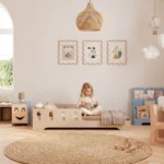 Lit enfant TILA 6 en contreplaqué naturel avec barrière ajourée et entrée basse, petite fille assise qui lit un livre.