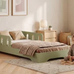 Lit enfant TILA 6 vert avec barrière latérale et découpes arrondies, petite fille jouant aux cubes sur le tapis à côté du lit.